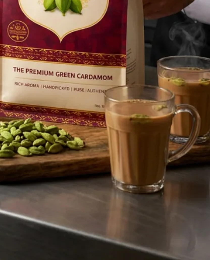 Glasses of masala chai beside a Panasva pouch and green pods