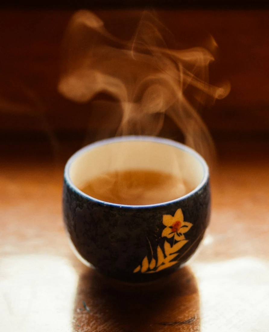 A cup of hot spiced tea on a wooden table, steam rising from it
